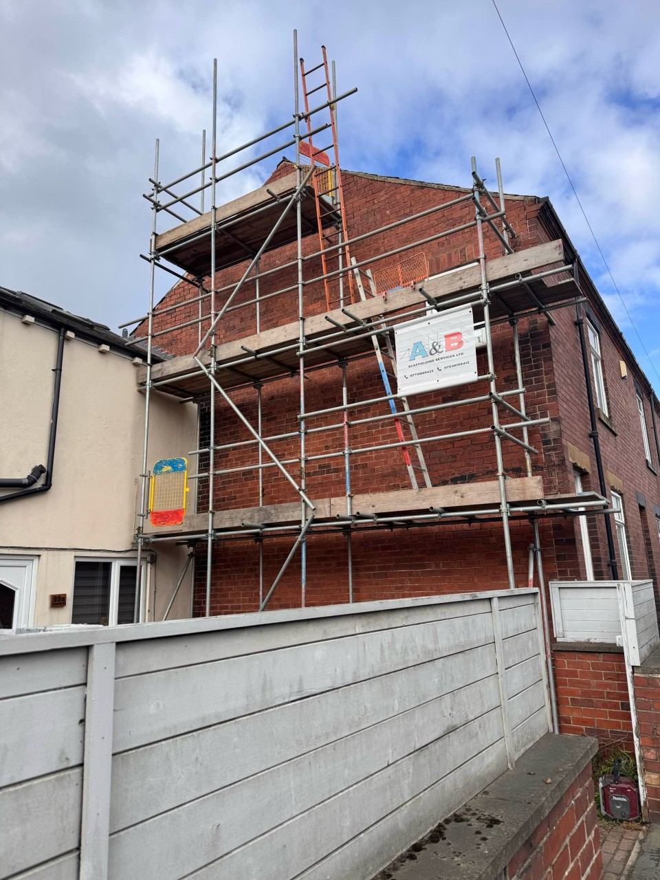 Scaffold running along the side elevation of a property beside a fenced boundary