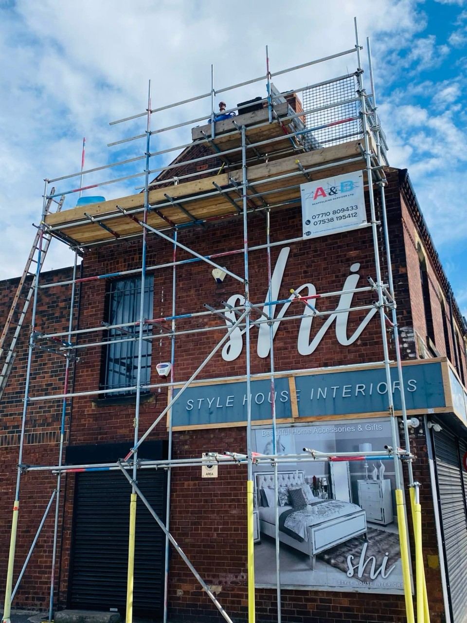 Scaffold on a brick building carrying a large printed advertising banner