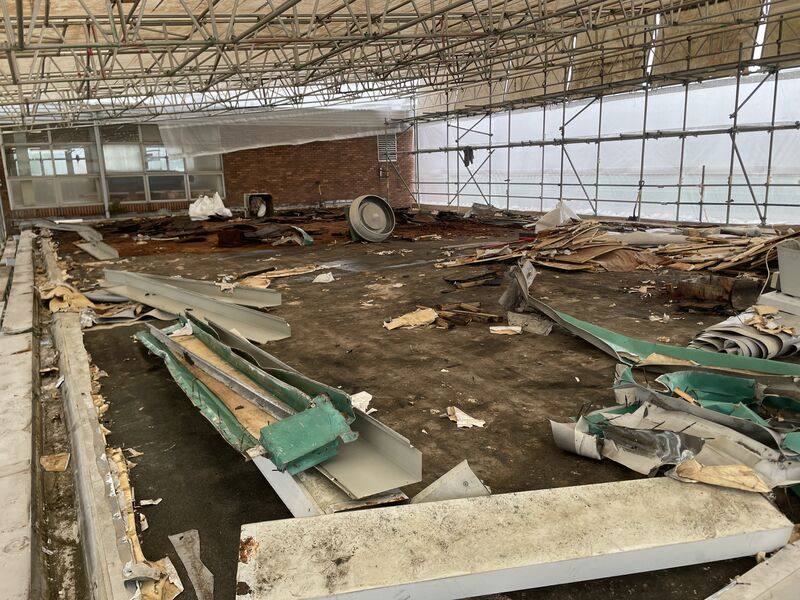 Large commercial roof strip-out under a temporary roof and scaffold