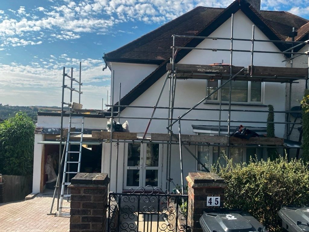 Scaffolded semi-detached house being externally rendered