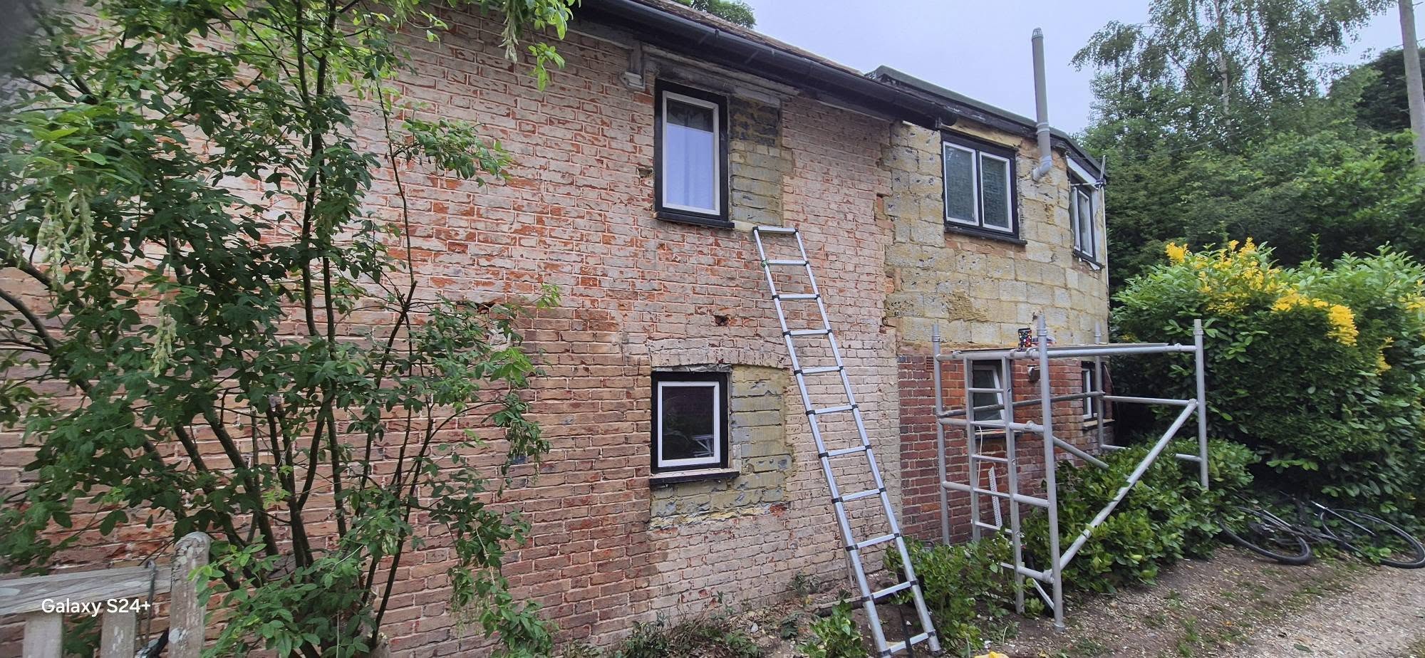Bare brick house front with scaffolding up before rendering