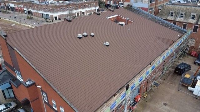 Aerial view of a large commercial pitched roof finished in terracotta tiles with scaffolding around the building