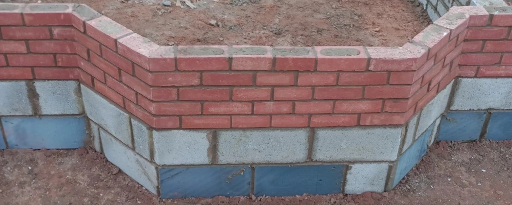 A curved red brick and blockwork retaining wall