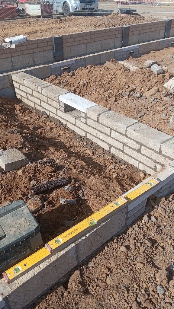 Blockwork and brick foundation course being levelled