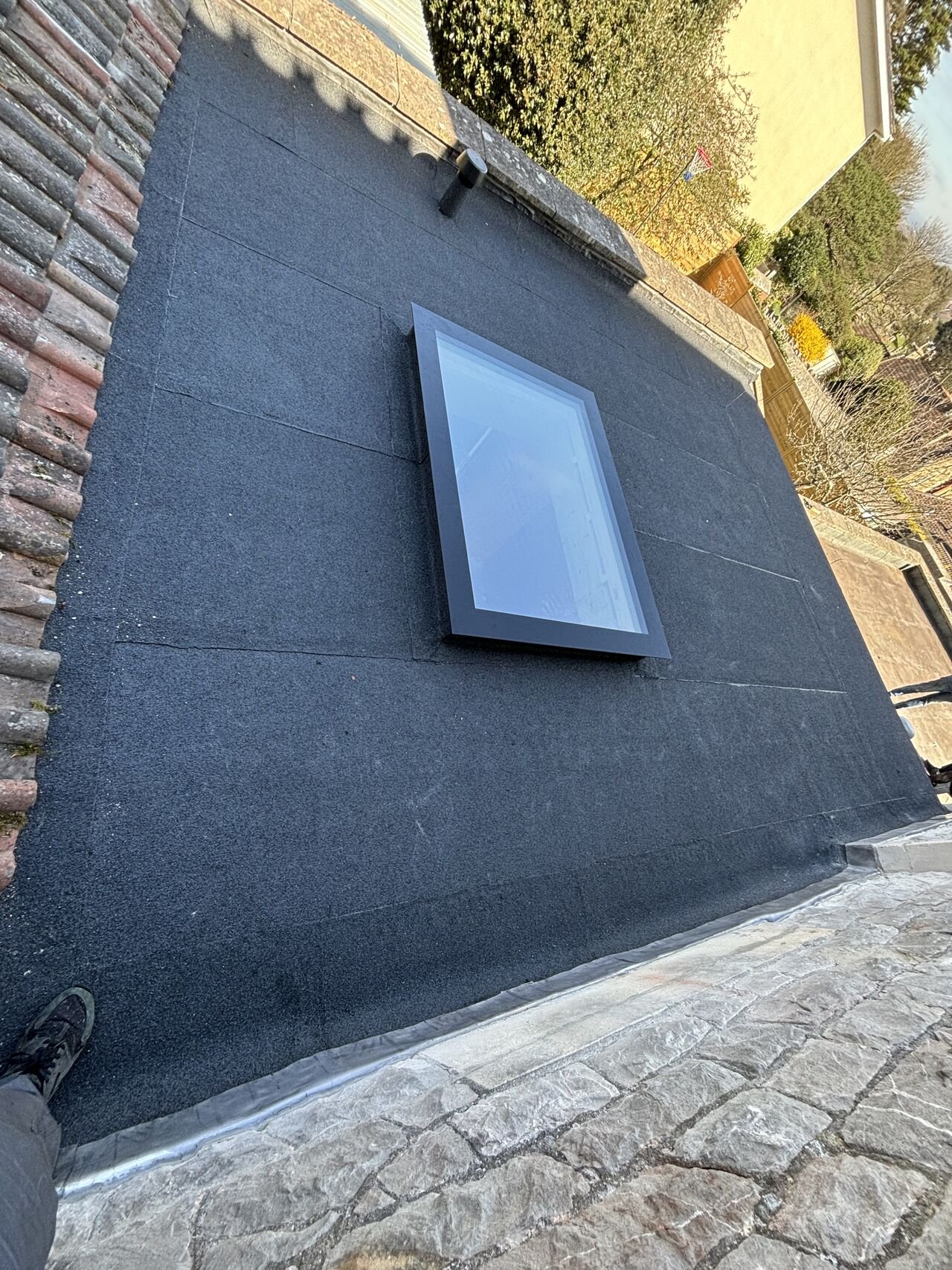 Finished torch-on flat roof with a newly installed skylight in sunshine