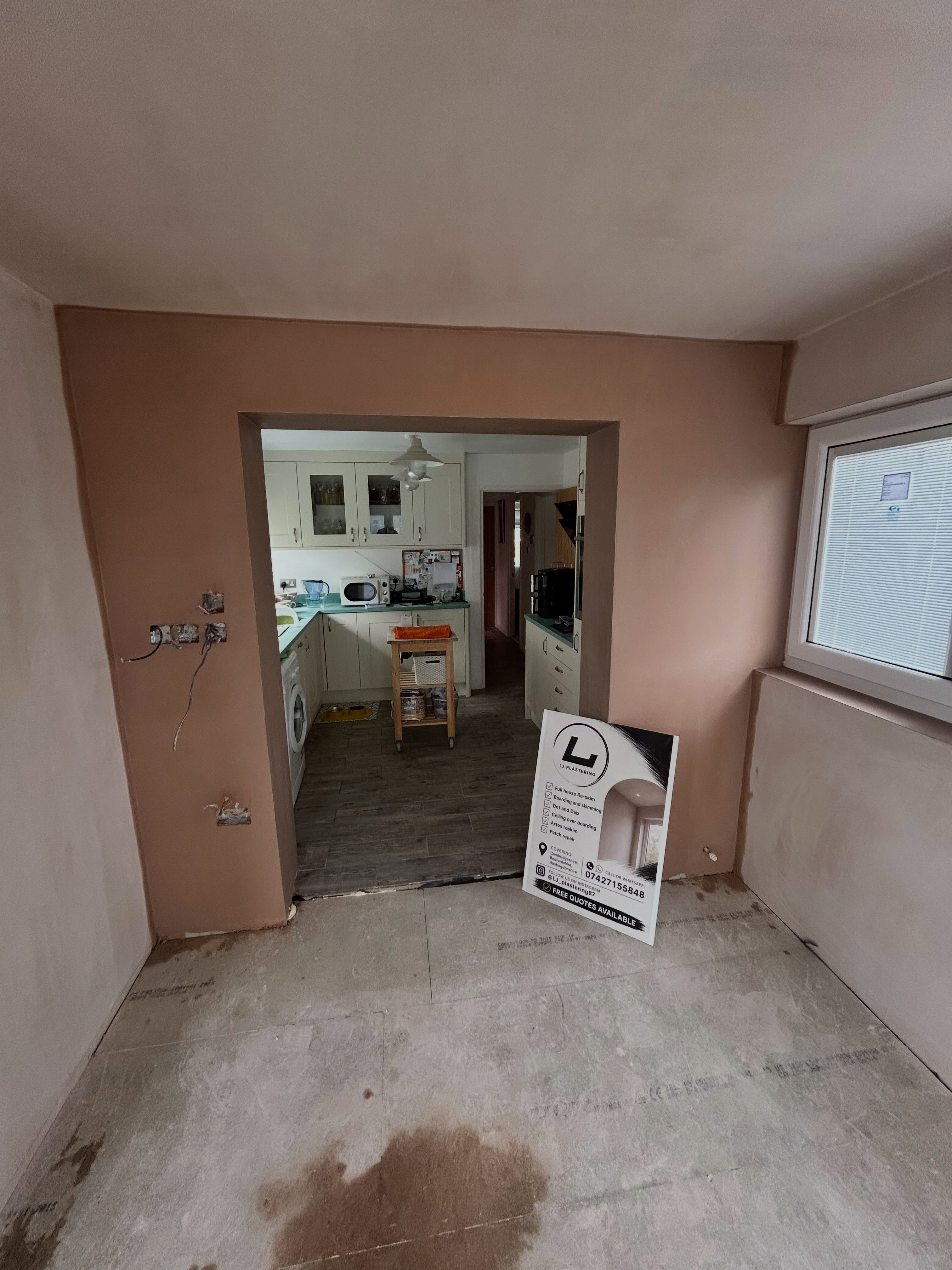 Fresh skim with an LJ Plastering advertising board in the room