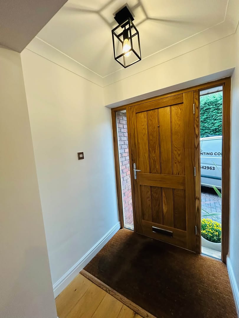 An open oak front door seen from inside a freshly painted white hallway.