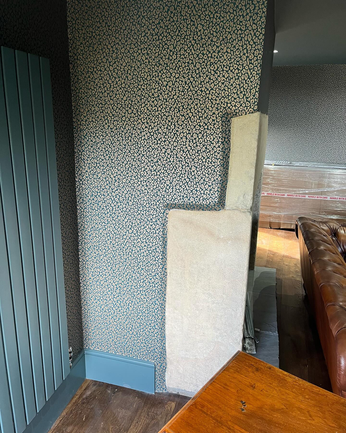 Patterned wallpaper with a teal sprayed designer radiator