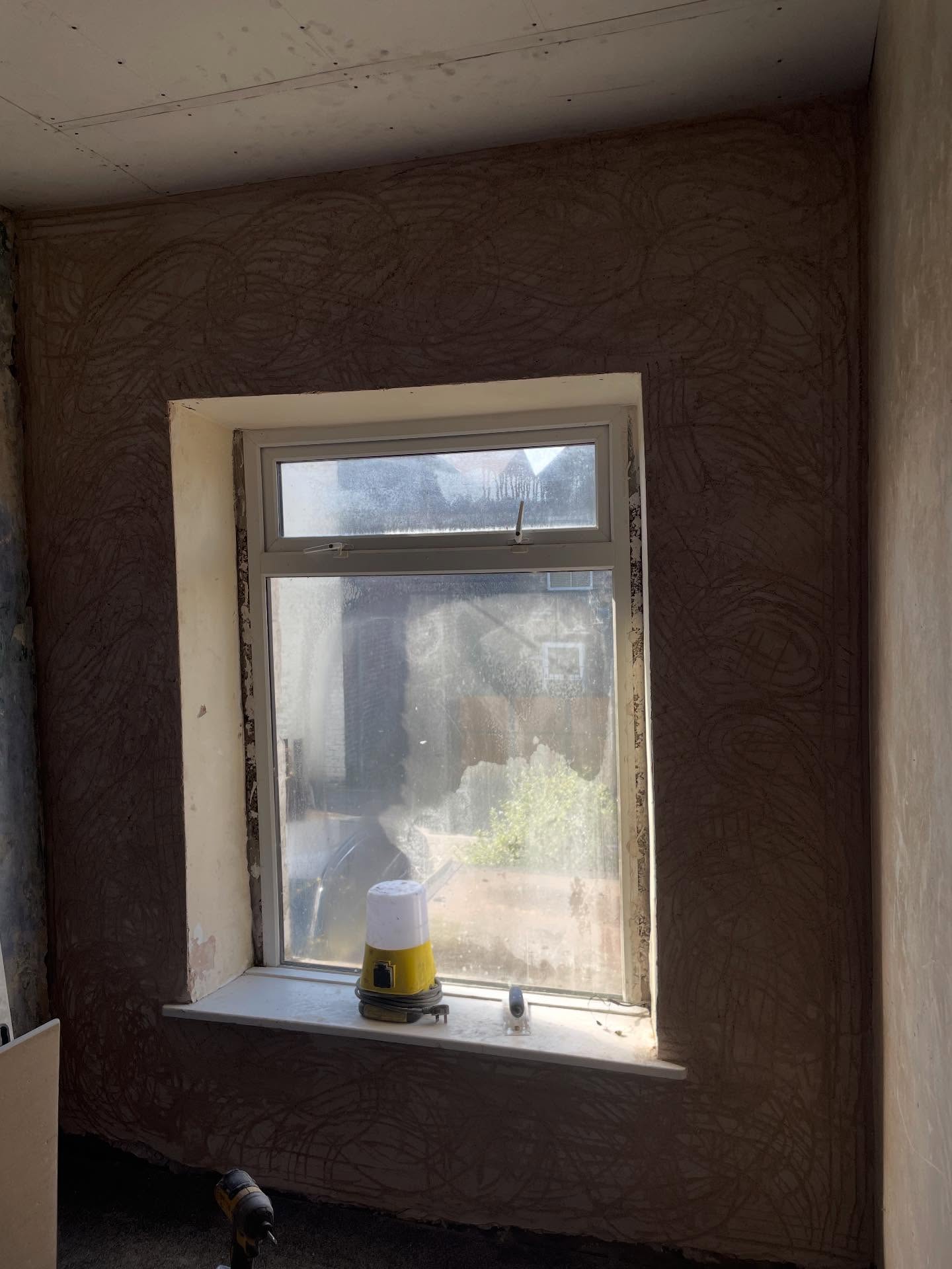 Old solid wall re-plastered with lime and repaired around a window