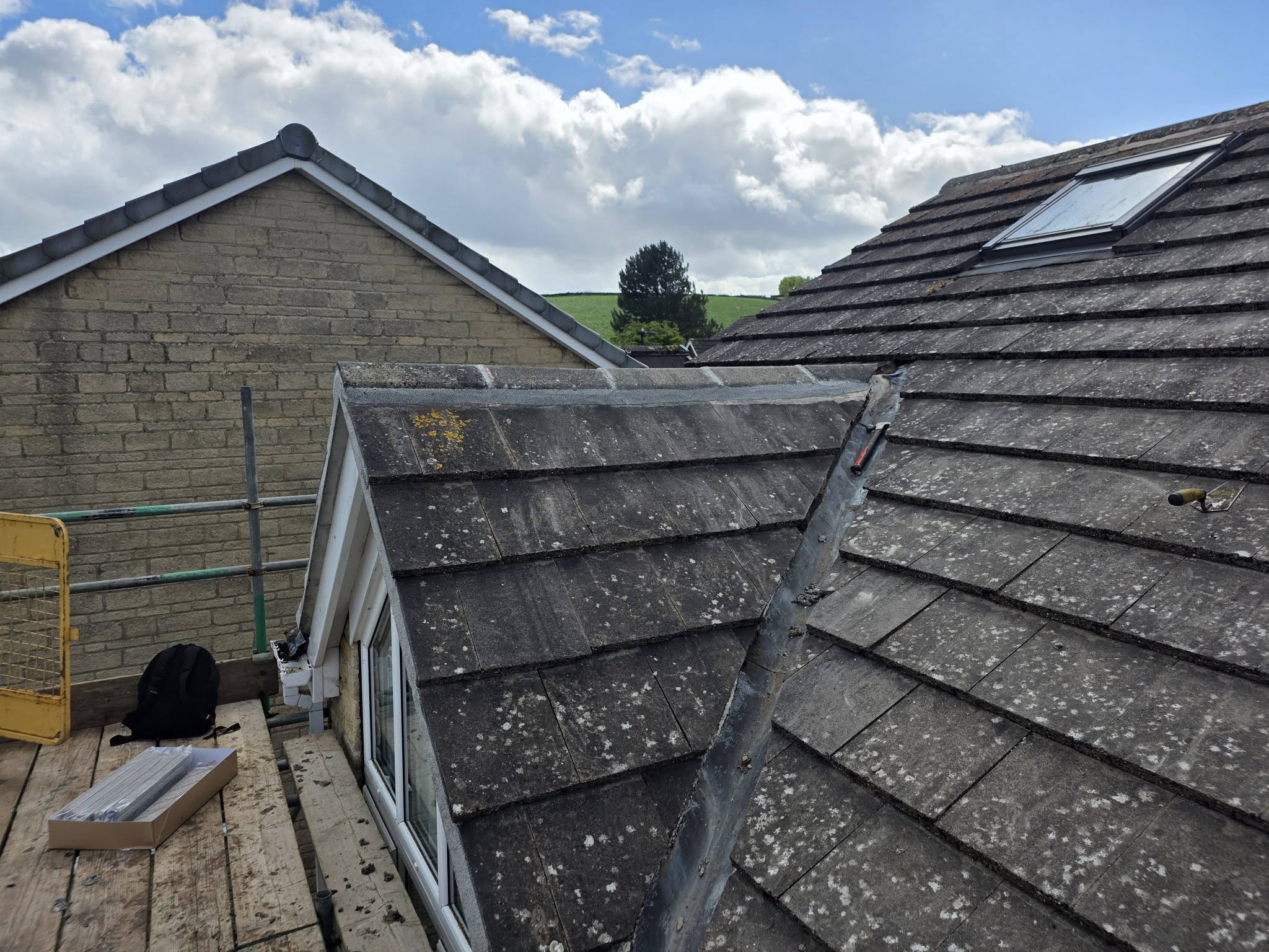 Dormer roof repair with freshly installed lead flashing under a bright sky