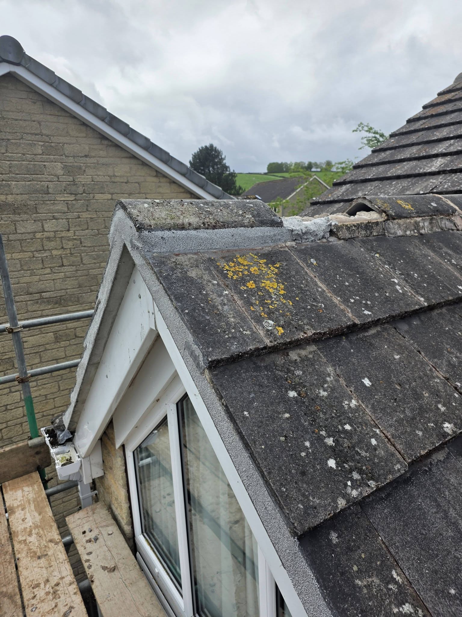 Freshly re-bedded and repointed ridge tiles above a dormer window