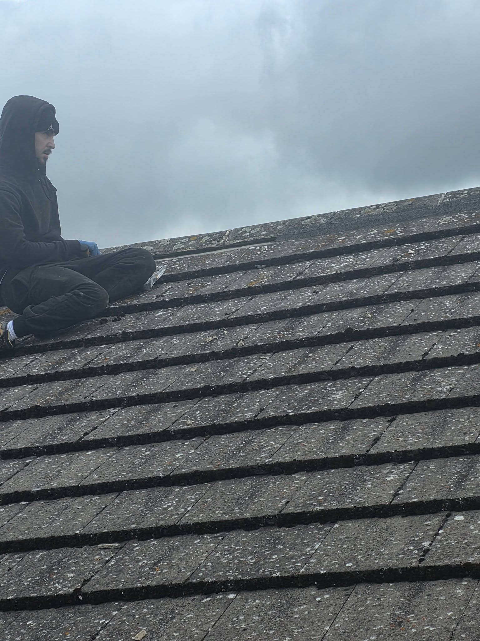 Trusty Roofers tradesman working at the ridge of a tiled pitched roof